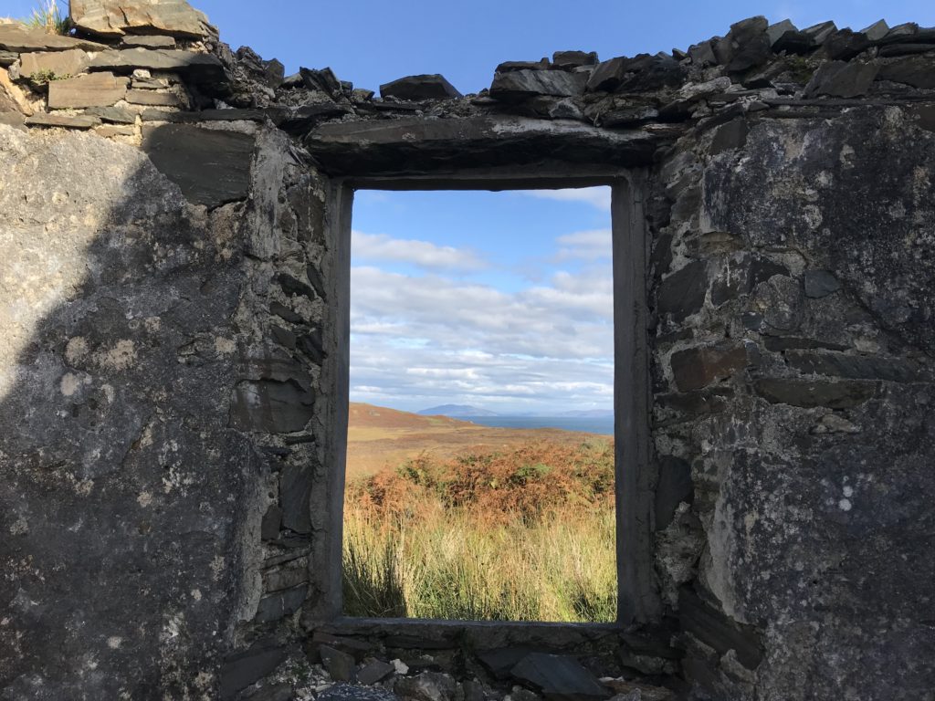 an empty window framing the sea. The frame is in a wall that has no roof above it.